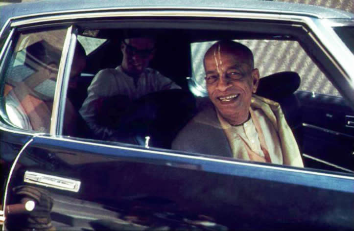 Prabhupada smiles from a car.